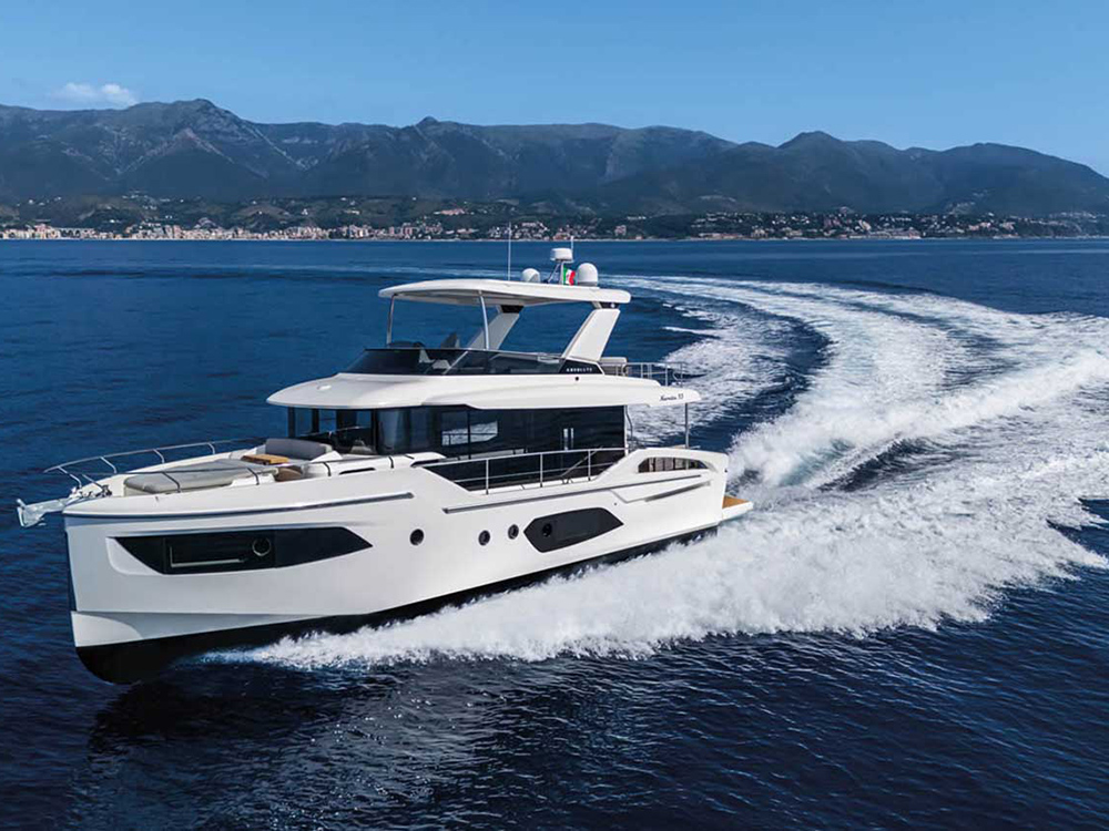 Absolute Navetta 53 cruising at speed across open water with coastal mountains in the background.