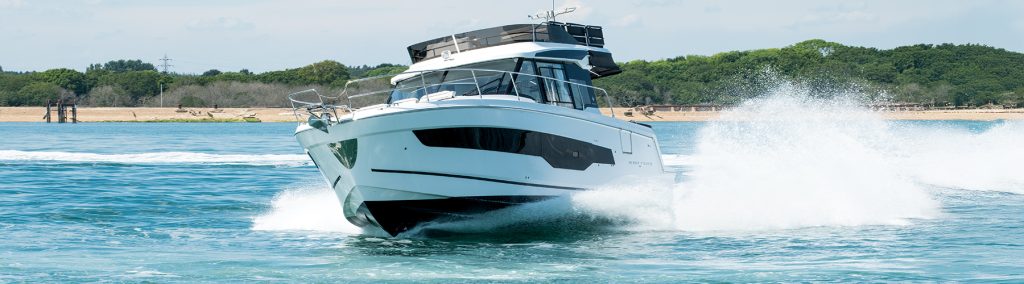 Jeanneau MF1295 motorboat driving towards camera on a blue sea