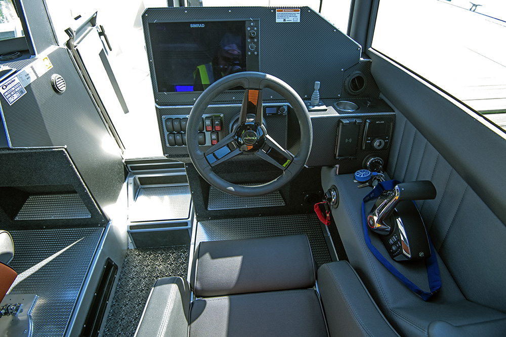Helm station of Ockelbo B25 CAB featuring Simrad display, steering wheel and throttle controls.