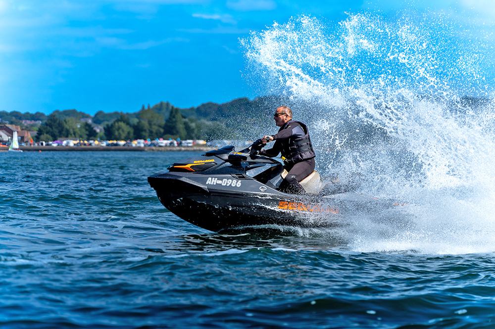 Jet ski rider carving through the water at speed, creating a large spray.