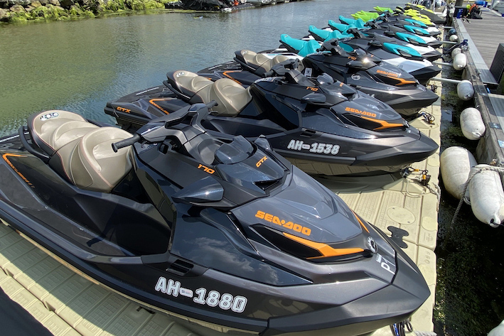 Sea-Doo jet ski fleet moored on a floating dock, lined up in a row.