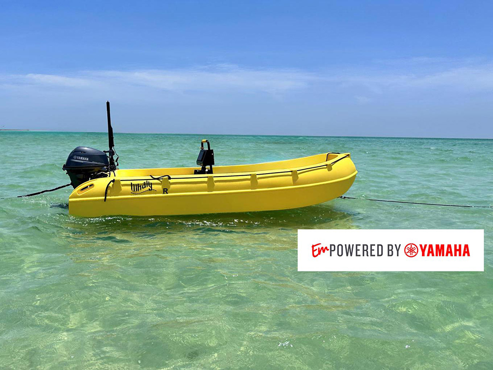 Bright yellow Whaly boat with a Yamaha outboard floating in clear shallow water under a blue sky.