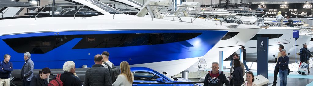 View of motorboat exhibition hall at boot Dusseldorf boat show with row of motorboats, bright blue motoryacht and car in the foreground