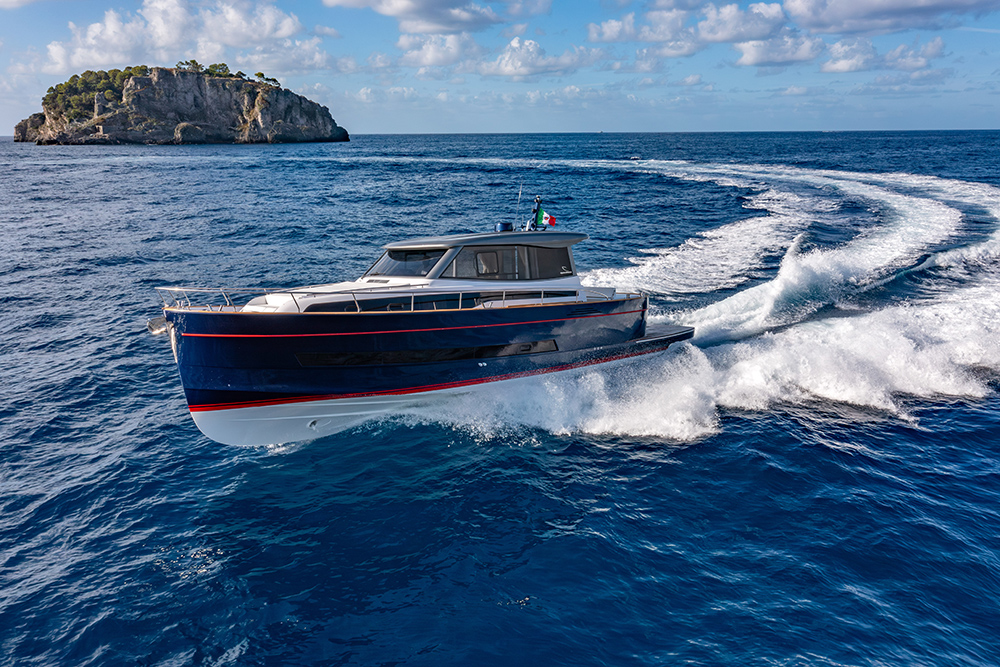 Apreamare Gozzo 48 Cabin cruising off a rocky Mediterranean island.